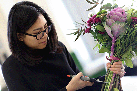 Student creating a bouquet of purple flowers